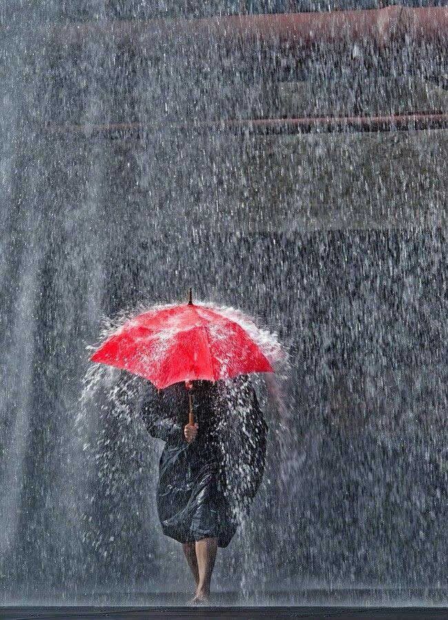 雨の中、赤い傘をさして立つ人